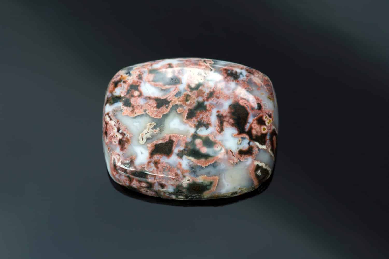 Natural ocean jasper cabochon loose polished gemstone. Barrel shaped, opaque gem with black and red veins pattern in white mossy base. Mined in Madagascar. Gemology, mineralogy, lapidary.